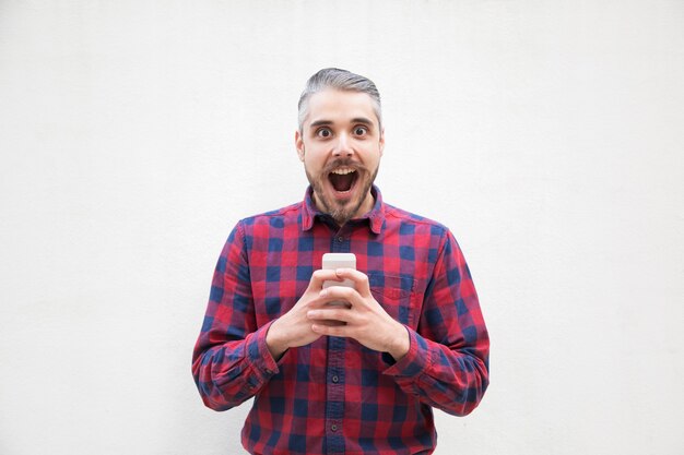 Hombre sorprendido con teléfono móvil mirando