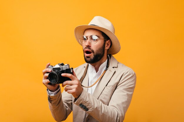 Hombre sorprendido en traje elegante posando con cámara retro