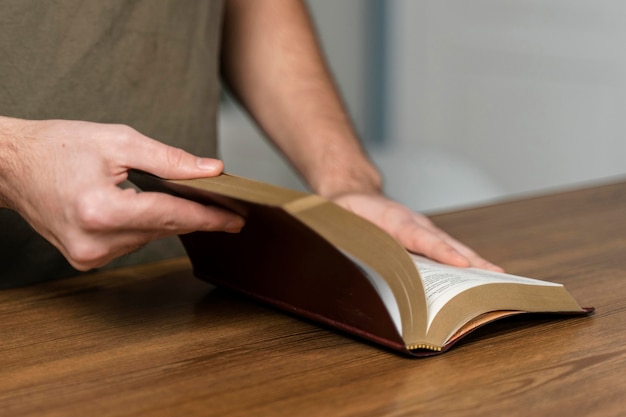 Foto gratuita hombre sosteniendo la biblia sobre la mesa