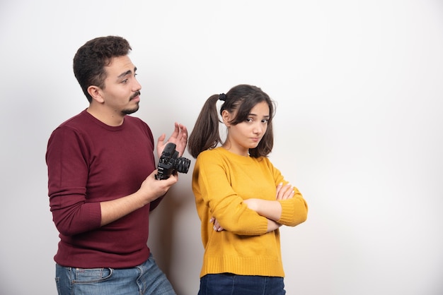 Hombre sosteniendo una cámara y mirando a una mujer joven.