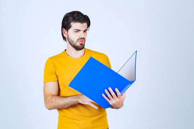 Hombre sosteniendo una carpeta azul y comprobando los informes.