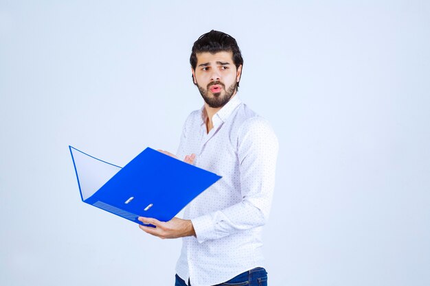 Hombre sosteniendo una carpeta azul y pensando