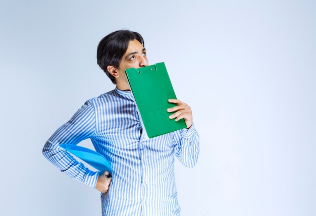 Hombre sosteniendo una carpeta de informe verde y pensando. Foto de alta calidad