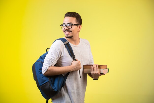 Hombre sosteniendo dos libros y sonriendo.