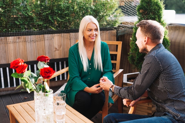 Hombre sosteniendo la mano de su novia sentado en un café al aire libre