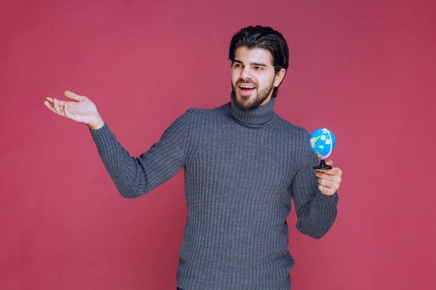 Hombre sosteniendo un mini globo y enviando saludos.