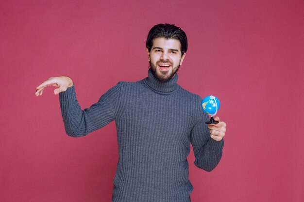 Hombre sosteniendo un mini globo y enviando saludos.