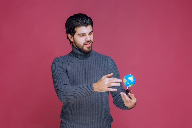 Hombre sosteniendo un mini globo y haciendo una presentación al respecto.