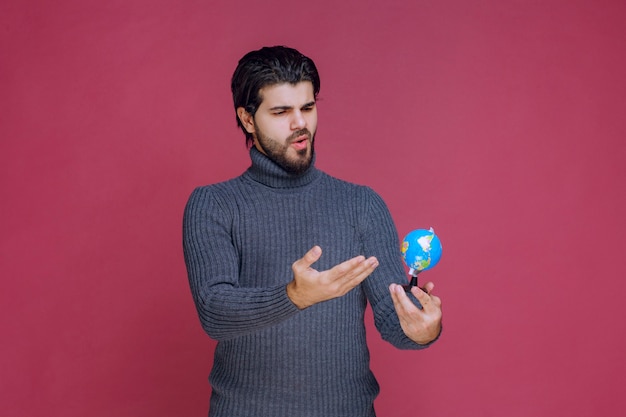 Hombre sosteniendo un mini globo y haciendo una presentación al respecto.