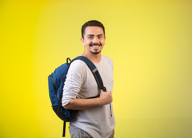 Hombre sosteniendo una mochila azul y sonriendo.