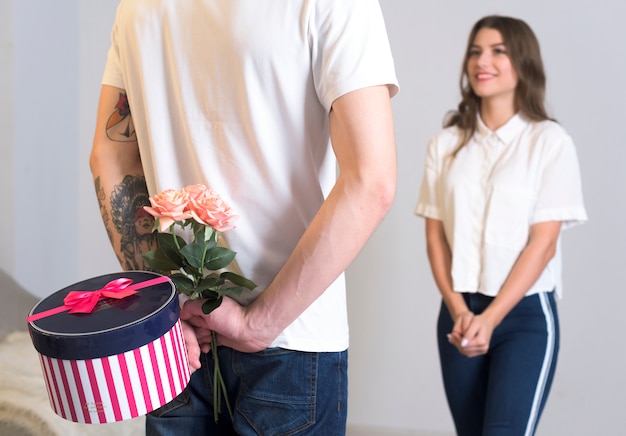 Hombre sosteniendo presente para mujer detrás de la espalda.