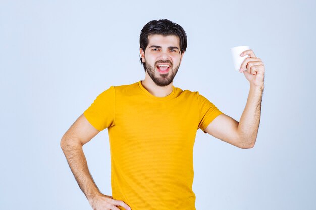 Hombre sosteniendo y promocionando una taza de café.