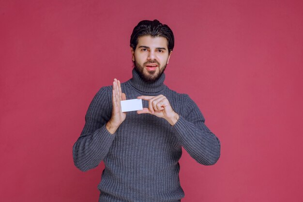 Hombre sosteniendo su tarjeta de visita y apuntando a ella.