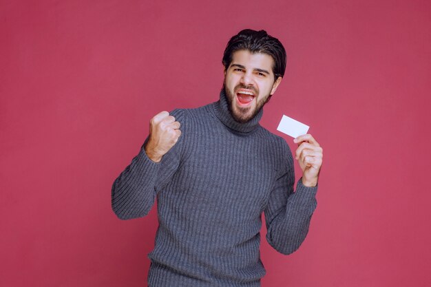 Hombre sosteniendo su tarjeta de visita, sintiéndose muy positivo y seguro de sí mismo.