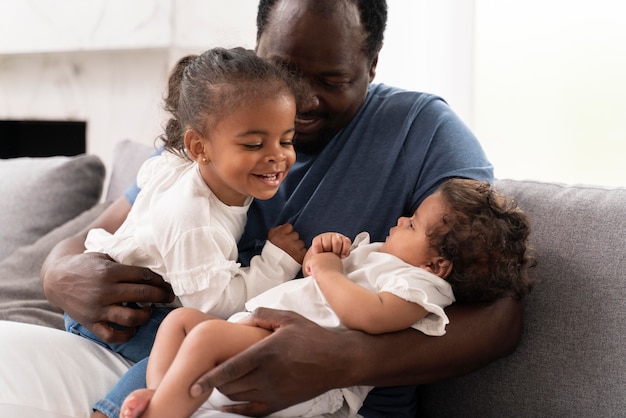 Hombre sosteniendo a sus hijas en sus brazos