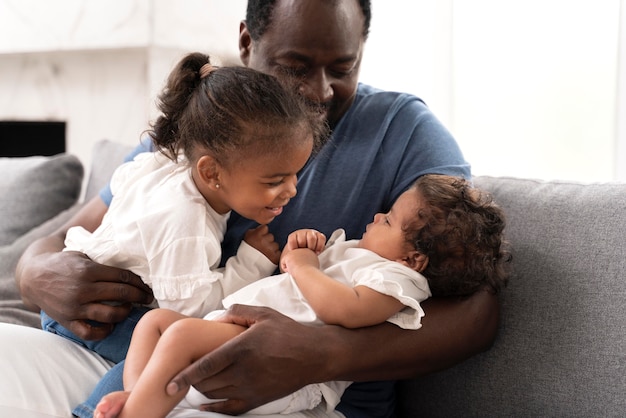 Hombre sosteniendo a sus hijas en sus brazos