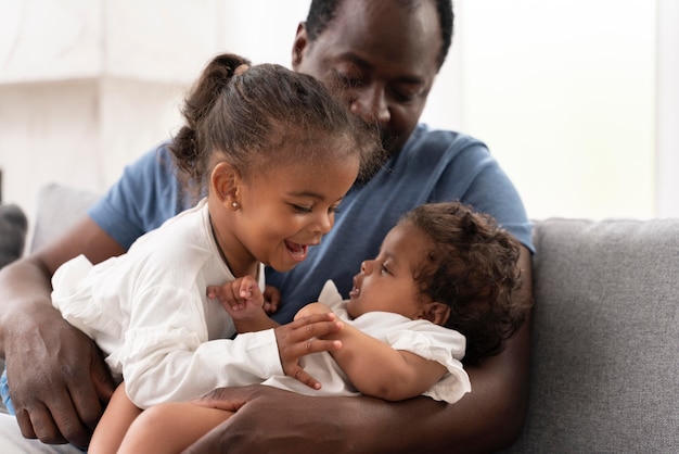 Hombre sosteniendo a sus hijas en sus brazos