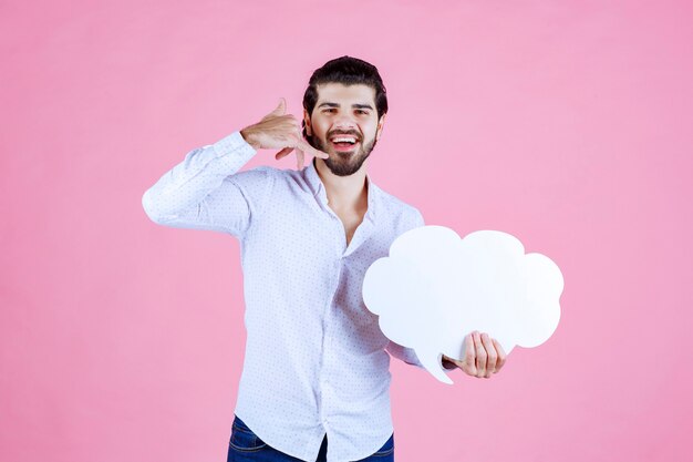 Hombre sosteniendo un tablero con forma de nube y pidiendo una llamada.