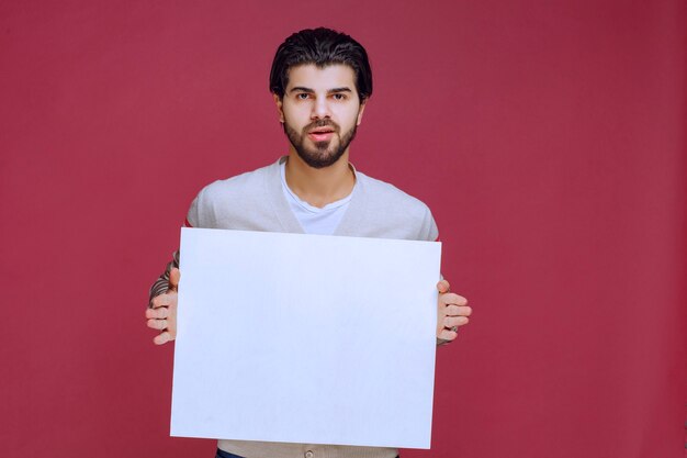 Hombre sosteniendo un tablero de ideas en blanco y haciendo presentación.