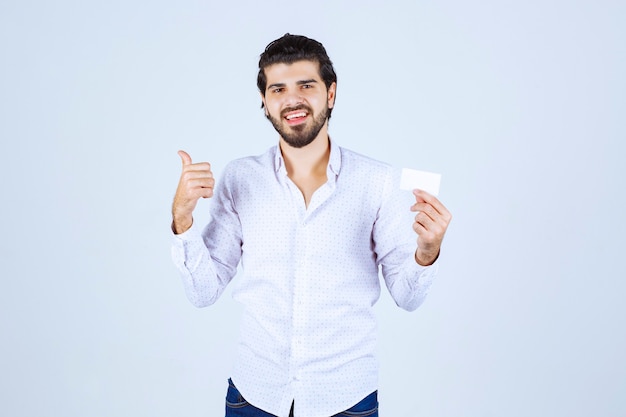 Hombre sosteniendo una tarjeta de visita y apuntando a alguien alrededor