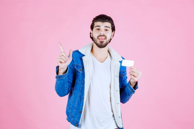 Hombre sosteniendo una tarjeta de visita y apuntando a alguien alrededor