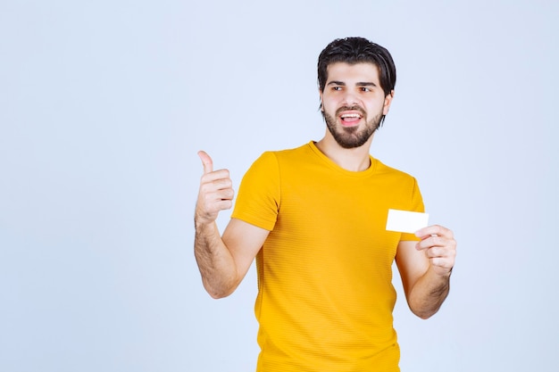 Hombre sosteniendo una tarjeta de visita y apuntando a su pareja.