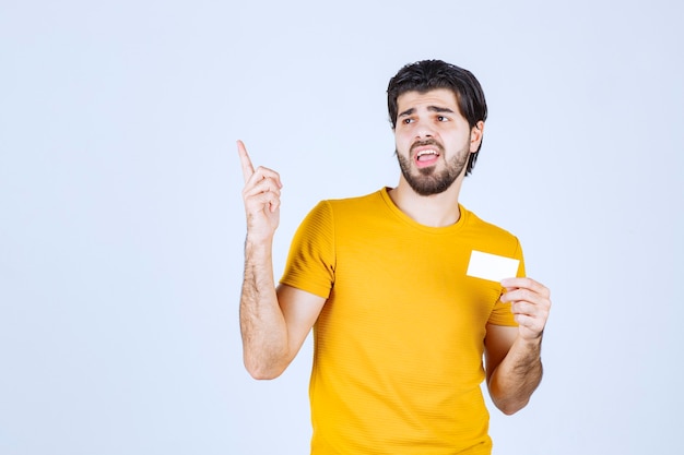 Hombre sosteniendo una tarjeta de visita y apuntando a su pareja.