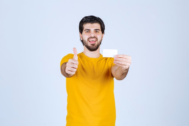 Hombre sosteniendo una tarjeta de visita y mostrando el pulgar hacia arriba.