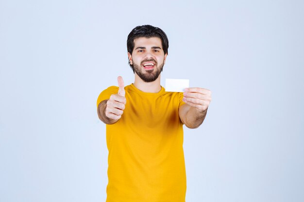 Hombre sosteniendo una tarjeta de visita y mostrando el pulgar hacia arriba.