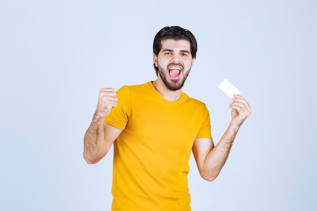 Hombre sosteniendo una tarjeta de visita y mostrando su puño.