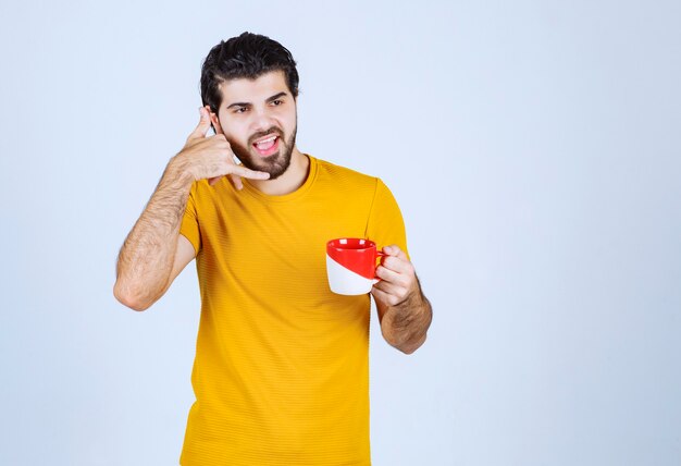 Hombre sosteniendo una taza de café y pidiendo una llamada.