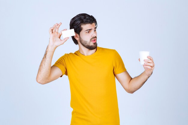 Hombre sosteniendo una taza de café y presentando su tarjeta de visita.