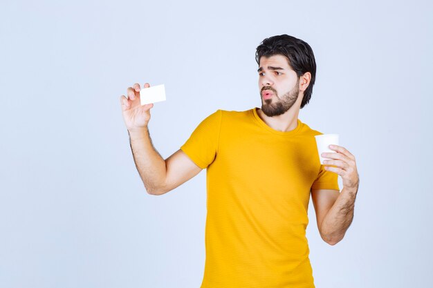 Hombre sosteniendo una taza de café y presentando su tarjeta de visita.