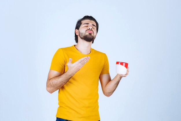 Hombre sosteniendo una taza de café y soplando el olor.