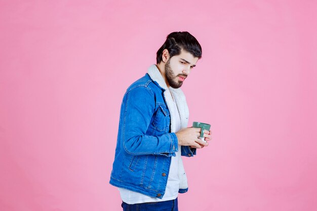 Hombre sosteniendo una taza de café y tomando café mientras posa