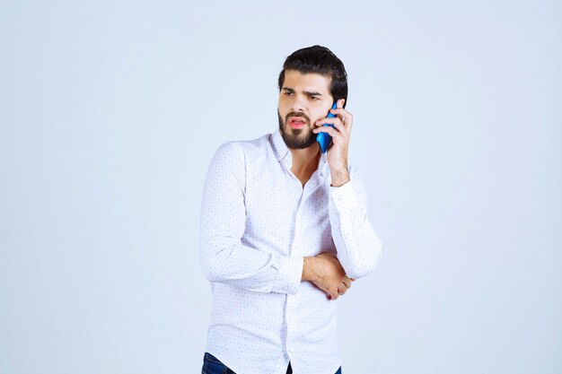 Hombre sosteniendo un teléfono azul y hablando