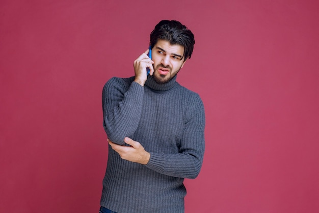 Hombre sosteniendo un teléfono inteligente en la oreja y hablando.