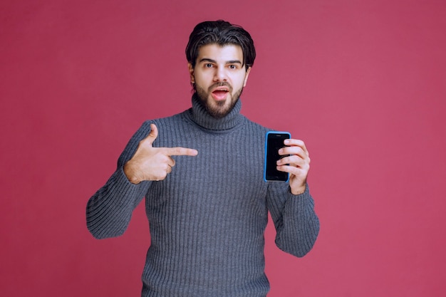 Hombre sosteniendo un teléfono inteligente y presentándolo a los clientes.