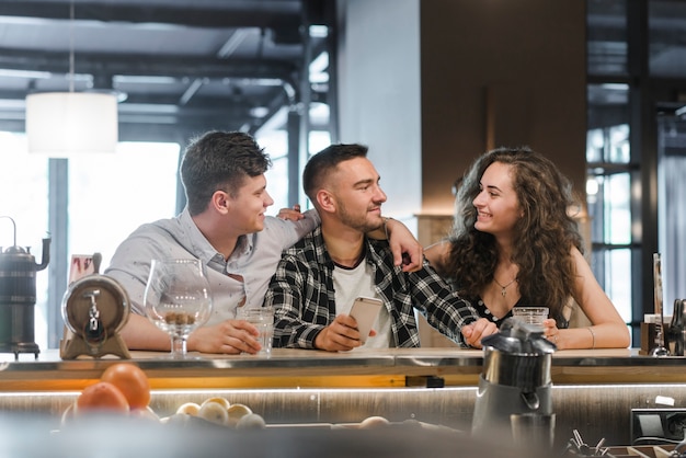 Foto gratuita hombre sosteniendo teléfono móvil disfrutando con amigos en el bar