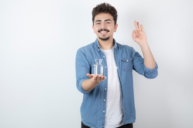 hombre sosteniendo un vaso de agua y dando señal de ok.