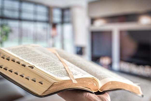 Foto gratuita un hombre sostiene una biblia contra la de la sala de estar.