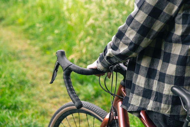 Foto gratuita un hombre sostiene un manillar de bicicleta y camina en el primer plano del bosque