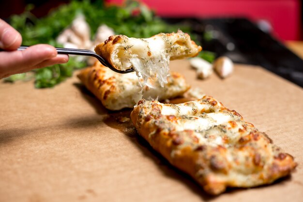 El hombre sostiene un pedazo de masa turca rellena de queso