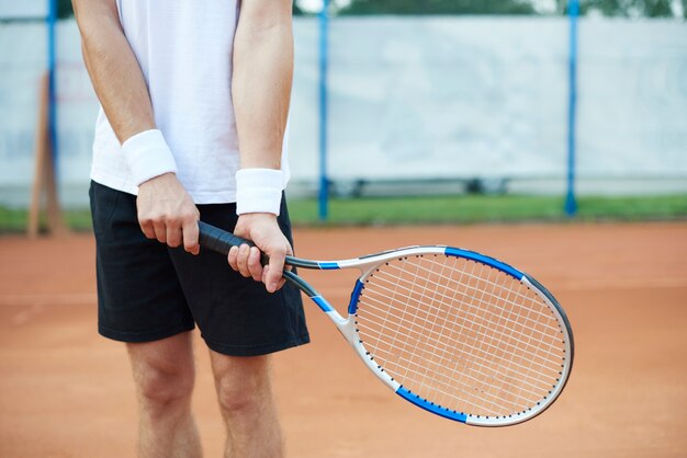 El hombre sostiene una raqueta de tenis.