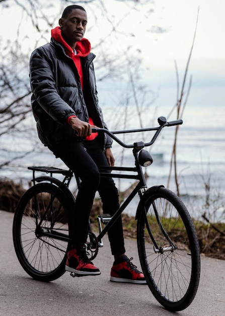 Foto gratuita hombre con su bicicleta junto a un lago