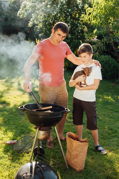 Hombre con su hijo cocinando comida en la parrilla de la barbacoa