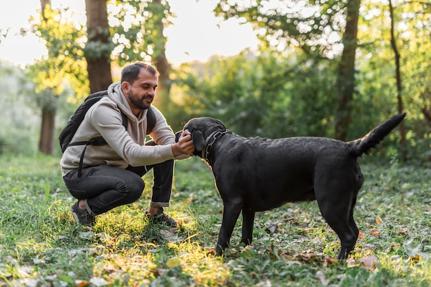 Hombre con su labrador negro jugando en el jardín en la hierba verde