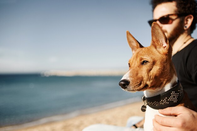 Hombre y su perro en la playa admirando el mar