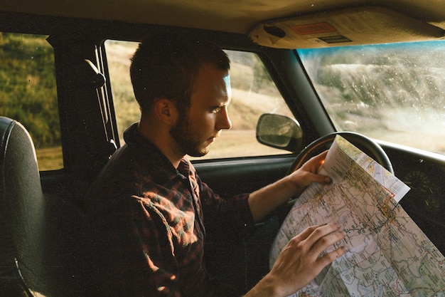 Hombre en su vehículo mirando el mapa y decidiendo adónde ir