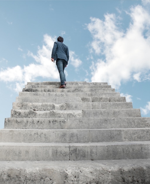 Foto gratuita hombre subiendo por escaleras al cielo